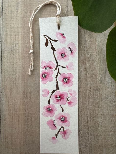 Beautiful bookmark featuring hand painted Japanese cherry blossom, the perfect gift for an avid reader and just in time for spring! Each bookmark is hand painted and original, and therefore will vary slightly. Details: Size 2"x 7" White watercolor paper Cotton string All packages will be shipped via US postal service, no tracking. Cute Bookmarks Painting, Hand Art Drawing Paintings, Cherry Blossom Bookmark, Diy Flower Bookmarks, Bookmarks Watercolor Ideas, Bookmark Watercolor Ideas, Hand Painted Bookmarks, Bookmark Painting Ideas, Japanese Bookmark