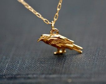 A richly detailed gold raven charm necklace.