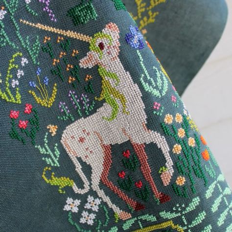 Sprouting Lupine, Kat on Instagram: "Some close-ups of The Unicorn's Garden 🌿⭐️  Alt Text Photo 1: A close up on a finished cross stitch with a long-tailed, cream unicorn with a green mane and long yellow horn. She is surrounded by several different flowers including tulips and lily of the valley.  Photo 2: A close up on cross stitches including part of a striped, reddish-brown tree trunk and a bush with dark orange flowers.  Photo 3: Another close up of the unicorn, this time showing more of the flowers above her including handing wisteria vines with purple flowers and fig-like leaves on the tree.  Photo 4: A close up on the cross stitched initials "K L H", which are enclosed in a fancy label-like motif with 4 white daisies.  #TheUnicornRestsInTheGarden #UnicornTapestry #UnicornCrossStit Cross Stitch Pillow Patterns Free, Vine Cross Stitch, Cross Stitch On Knitting, Cross Stiching Ideas Modern, Cross Stitch Unicorn, Unicorn Cross Stitch, Cute Cross Stitch Patterns Free, Crochet Cross Stitch, Cross Stitch Flower