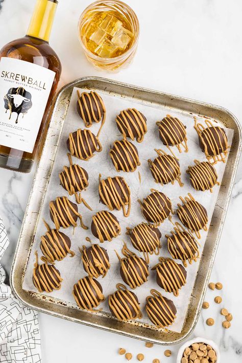 Whiskey Balls on a baking sheet with a bottle of Screwball whiskey beside it. Screwball Whiskey Dessert Recipes, Screwball Peanut Butter Whiskey Balls, Screwball Whiskey Balls, Dough Ball Whiskey Recipes, Boozy Snacks, Whiskey Balls Recipe, Boozy Balls, Whiskey Desserts, Whiskey Balls