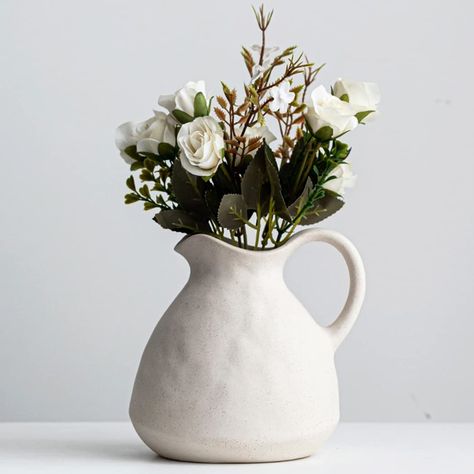 PRICES MAY VARY. Farmhouse Pitcher for Decor:This white pitcher vase is giving you full country vibes,with unique milk jug shape, pretty handle and spout.Plus,the vintage vase has a special sand texture that is almost not visible from the picture,but you can feel it,which gives the terracotta vase a quiet,plain look and makes it perfect wabi sabi decor,farmhouse decor,boho decor and vintage decor. Great Table Centerpieces:Instead of regular smooth texture,this stoneware white vase adopts a speci Farmhouse Pitchers, Farmhouse Vase, Shelf Decor Living Room, Vintage Jugs, White Pitcher, Rustic Ceramics, Jug Vase, White Ceramic Vases, Pitcher Vase