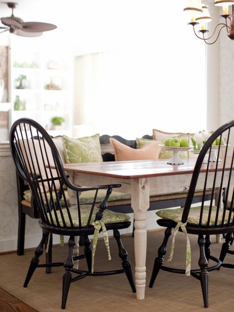 This country dining setting features a farmhouse table with black Windsor chairs and bench to give the space a more causal feel. Green-and-white-pattern cushions pad the seats with matching throw pillows on the bench. Neutral pillows are mixed in complementing the distressed wooden table and neutral rug. Farmhouse Dining Room Rug, Country Dining Tables, Trendy Farmhouse, Dining Room Chair Cushions, Windsor Chairs, Kitchen Chair Cushions, Country Dining Rooms, Farmhouse Dining Chairs, Dining Room Seating