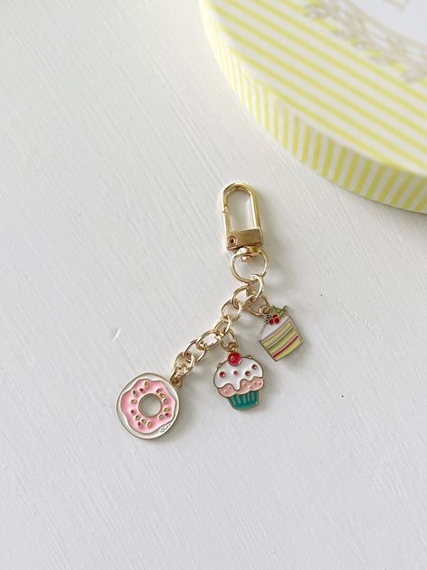 "This accessory is a sweet treat! Our enamel cupcake keychain is a beautiful keychain featuring not only a cute cupcake design, but also includes two delightful charms--a donut and a slice of cake. Its compact size and lightweight design make it easy to carry around, so you can showcase your love for all things sweet wherever you go. This is also a great gift idea! PLEASE NOTE: Our keychains are not to be used as a toy and not suitable for small children.  Description: Cupcake Charm Size: 1/2\" Cupcake Keychain, A Slice Of Cake, Straw Holder, Christmas Cruises, Cute Cupcake, Cupcake Charms, Slice Of Cake, Backpack Accessories, Keychain Purse