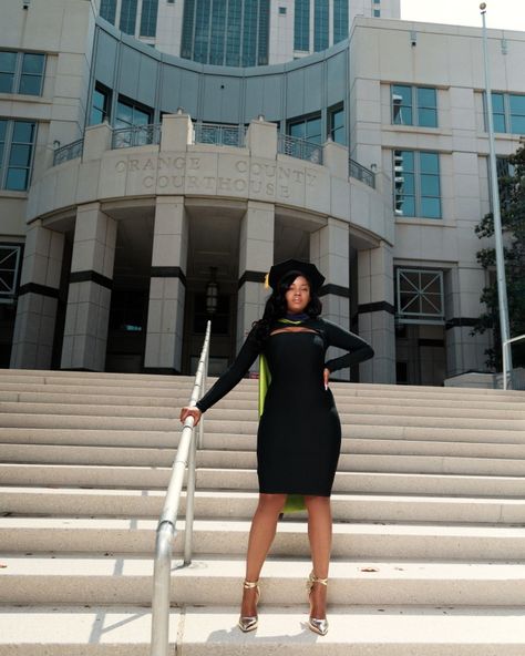 Black girl, standing on staircase, holding on to railing, in front of the Orange county courthouse sign taking graduation pictures. She is wearing all black, with gold shoes. She is wearing her tam on her head and her hood across her back. Above the Orange County Courthouse sign are windows going across. Bright sunny day. Medical School Graduation Outfit, Law School Graduation Outfit, Doctoral Graduation Pictures, Medical School Graduation Pictures, Lawyer Photoshoot, Doctorate Graduation Pictures, Law School Graduation Pictures, School Graduation Outfit, School Graduation Pictures