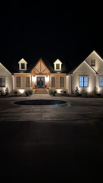 Nikki • Modern Farmhouse on Instagram: "This is one of my favorite upgrades we made. I absolutely love the look of our house at night. It’s all connected to a timer set to automatically come on at dusk until dawn. Is this something you have considered for your home? #frombuildtobuilt #uplighting #premierlandscape #customhomes #homeswithpurpose #whitebrick #landscapelighting #ourbuildjourney #housebuildingtips" Home Exterior Lighting At Night, Ranch House Outdoor Lighting, Lights On Front Of House, Exterior Up Lighting On House At Night, House Landscape Lighting, Exterior Uplighting House, Lights For Outside House, Lights On House Exterior At Night, Exterior Home Lighting Ideas