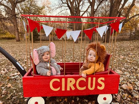 Twin toddlers dressed as circus animals (a lion and elephant) riding in a DIY cage made from a wagon. Circus Toddler Costume, Red Wagon Halloween Costume, Halloween Costume Wagon Ideas, Diy Lion Cage Wagon, Lion Cage Circus Diy, Circus Wagon Halloween, Wagon Costumes For Kids, Toddler Circus Costume, Wagon Costumes For Babies