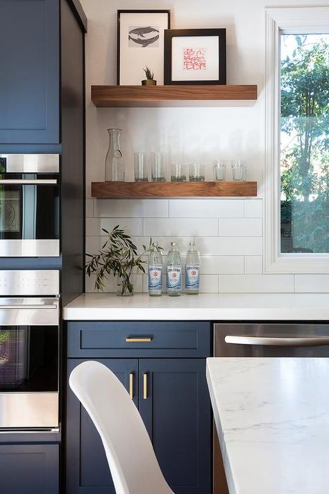 Fantastic kitchen features navy blue shaker cabinets adorned aged brass pulls paired with white quartz countertops that resemble marble and a white stacked tile backsplash. Sink Window, Kitchen Colours, Navy Kitchen, Floating Shelves Kitchen, Kabinet Dapur, Young House, Reference Pics, New Kitchen Cabinets, Blue Cabinets