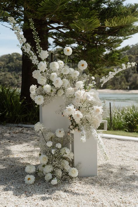 Whimsical, delicate white florals for Olivia & Scotts beachside wedding at the Cove Jervis Bay. Set to a backdrop of Jervis Bay's crystal clear waters, Olivia & Scott chose to feature asymmetrical plinth designs for their ceremony. Captured by Ben Sowry. Wedding Floral Mood Board, Timeless Wedding Altar, Wedding Ceremony Pillar Florals, Pillar Alter Wedding, White Rose Reception, White Plinths Wedding, Florals On Pedestals, Floral Columns Wedding Ceremony, Flower Plinth Wedding