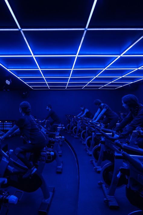 Refuse’s dark workout room hones a nightclub vibe thanks to navy blue walls and UV lights sunk into its waffle slab ceiling.  #design #gyms #architecture Blue Gym Interior, Blue Gym Aesthetic, Small Gym Design, Blue Light Room, Half Garage Gym Ideas, Home Exercise Room, Half Garage Gym, Garage Gym Design, Dark Gym