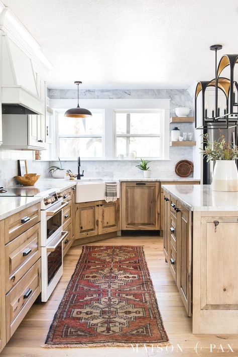 Get all the sources for this beautiful white and wood kitchen with white oak flooring, black and gold accents, marble backsplash, and quartzite counters. Wood Kitchen Cabinets White Appliances, Maple Cappuccino Cabinets, Adler Wood Cabinets, White And Wood Kitchen Cabinets, Kitchen With Natural Wood Cabinets, White And Wood Cabinets, Natural Maple Kitchen Cabinets, White And Oak Kitchen, Natural Kitchen Cabinets