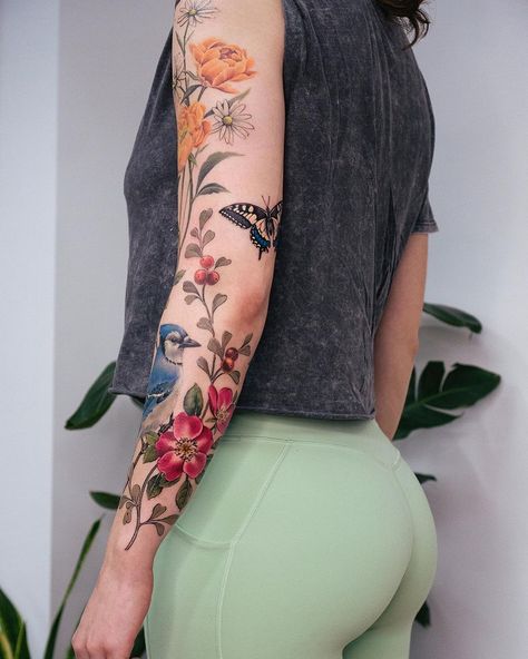 Top 1 Tattoo Page on IG (@tattooassist) | Instagram Colored Flower Back Tattoo, Colored Nature Tattoo, Watercolour Tattoo Sleeve, Full Color Floral Sleeve Tattoo, Cottagecore Tattoo Design, Whimsical Garden Tattoo Sleeve, Botanical Sleeve Tattoo Wild Flowers, Mixed Floral Tattoo, Nature Arm Tattoos For Women