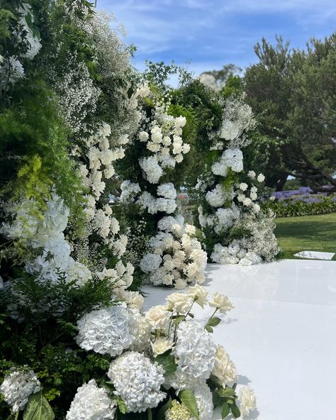 An epic summery ceremony backdrop featuring an abundance of hydrangeas, roses, baby’s breath, and vibrant greenery. We kept the floral varieties simple, grouping them en masse to create a bold and modern aesthetic! 🍃🤍 #floraldesign #flowersstgermain #summerwedding #hydrangea #modernbride #floralinstallations #ceremonyflowers #outdoorweddingceremony #melbourneflorist Hydrangea Wedding Ceremony, Hydrangea Isle Wedding, Hydrangea Cloud Wedding, Wedding Ceremony Hydrangea, Hydrangea Floral Installation, Baby S Breath, Ceremony Flowers, Ceremony Backdrop, Outdoor Wedding Ceremony