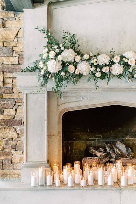 This wedding ceremony mantel design included white hydrangea, fluffy white ranunculus, lisianthus, snowflake spray roses, white o'hara garden roses, italian ruscus, olive leaf and mixed eucalyptus varieties.  Photo: Heidrich Photography Venue: The Lake House, Calgary Alberta  #calgaryweddings #whiteweddingflowers #fireplacemantelflowers #weddingmantelflowers #flowersbyjanie #calgaryweddingflorist #lakehousecalgarywedding #whiteoharagardenrosewedding #whitehydrangea Wedding Mantle Decor, Wedding Fireplace Decorations, Mantel Flowers, Wedding Mantle, Wedding Fireplace, Wedding Ceremony Ideas, White Pillar Candles, Hydrangeas Wedding, Wedding Winter