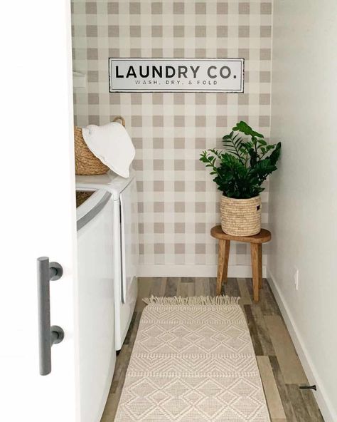 Beige gingham laundry room wallpaper is decorated with a white vintage sign and a wooden stool holding a woven basket planter. A beige woven fringe runner rug is laid in front of a white washer and dryer set. White Washer And Dryer, Laundry Room Wallpaper Ideas, Vintage Signs Decor, Quatrefoil Wallpaper, Room Wallpaper Ideas, Memorial Day Thank You, Black Metal Shelf, Grey Laundry Rooms, Beige Gingham