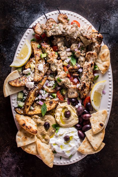 The Ultimate Greek Chicken Souvlaki Platter is loaded with tender grilled chicken skewers, pita bread, Greek potato wedges, hummus, tzatziki, melitzanosalata, kalamata olives, feta, and other goodies. The perfect meze assortment for any feast or party! Souvlaki Platter, Greek Potato Wedges, Souvlaki Chicken, Chicken Hummus, Greek Meze, Greek Chicken Souvlaki, Greek Dinners, Grilled Chicken Skewers, Greek Potatoes