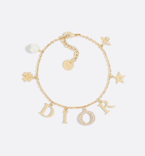 The Dio(r)evolution bracelet is a creation with a modern aesthetic. The Dior letters are suspended from a gold-finish metal chain, while the pavé of silver-tone crystals adorning the letter O adds a luminous touch. The design is embellished with a white resin pearl and signature Dior symbols, including stars, the clover and the bee. The sophisticated bracelet can be combined with other creations from the Dio(r)evolution line.. Dior Charm Bracelet, Dior Armband, Dior Bracelet Gold, Dior Jewelry Bracelets, Bracelet Dior, Dior Jewellery, Dior Bracelet, Bracelets Luxury, Resin Pearl