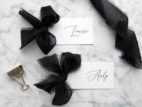 These Bow Chiffon Ribbon Place Cards are elegant in design and will suit a whole range of wedding styles and venues. The luxury frayed edge chiffon ribbon bow is available in 40 colours and names are printed on a beautiful 260gsm hammered white card. Place cards pictured have the black ribbon. If you don't see the colour you are after, please pop me a message and I'll let you know if I can get it. <> These can be ordered on my website for 10p less per card and in exact quantities rather than sets of 5. Visit: https://www.letlovesparkledesign.co.uk/product-page/bow-chiffon-ribbon-place-cards If you would prefer to place your order on Etsy, simply choose your colour from the drop down list, select the quantity of place cards required and add to basket. Once you have completed your order plea Bow Napkin Wedding, Black And White Place Cards, Bow Place Setting, Bow Name Cards, Bow Place Cards, Name Cards Wedding Table, Bow Wedding Decor, Card Name Design, Table Place Cards Wedding