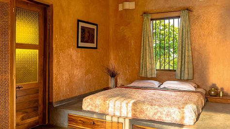 The guest room features hand-rendered lime-plaster walls, curtains block-printed by Odia craftsmen, and a low, in-built, polished-cement bed platform; the woven cane wardrobe and steel lampshades were designed and built at Andagere Architects’ workshop. Cement Bed, Cane Wardrobe, South Indian Design, Lime Render, Polished Cement, Lime Plaster, Cottage Interior Design, Village Home, Bed Platform