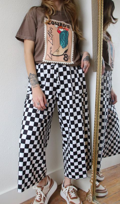 Our mid-rise Checkmate Pants are here to take trousers to another level. With a comfy elastic waistband and a wide-leg fit, they'll have you looking stylish and feeling cozy! Perfect for a casual day out, the washed black and white checkered print creates a bold and stylish look. Go ahead, make your move! These run very generous. I always wear an 8/10 or a large and I wear a medium in these comfortably. Size down please. Mid-rise waist Pockets Comfy elastic waistband Wide leg fit Washed black an Outfits With Checked Pants, Mid Size Eclectic Fashion, Comfortable Punk Outfits, Linen Pants Plus Size Outfits, Punk Teacher Outfits, Pattern Trousers Outfit, Adronymous Outfits, Funky Business Casual Outfits, Black And White Checkered Pants Outfit