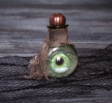 The creepy miniature bottle in dollhouse scale 1:12 is a great eyecatcher for Halloween. The small bottle is made of green glass, and filled with a magical tincture. The front of the bottle is dekorated with a glass pupil. The bottle-neck is adorned with a rag scarf. The bottle is closed with a bronze bead. Measurements: Height: 3.1 cm / 1.22 inch Width: 2 cm / 0.79 inch Depth: 1 cm / 0.39 inch IMPORTANT: The prise is for the bottle only. I added the owls for illustration only. Attention: This a Mini Glass Bottles Ideas, Haunted Dollhouse Diy Ideas, Medicine Bottle Crafts, Scary Halloween Crafts, Dollhouse Halloween, Halloween Potion Bottles, Halloween Apothecary, Halloween Potions, Magic Bottles