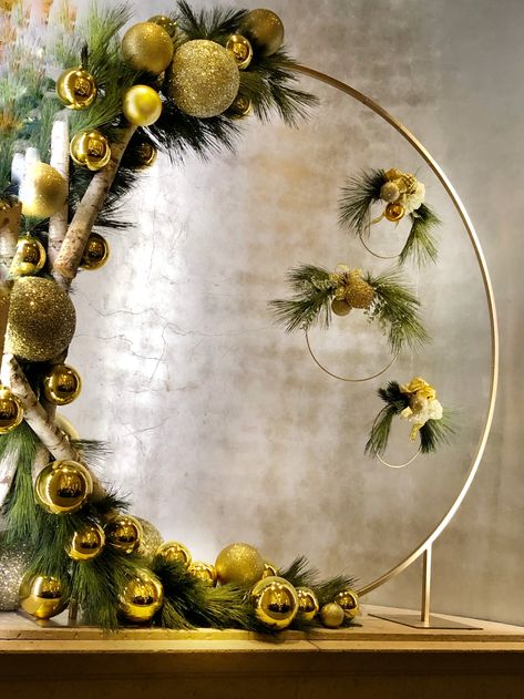 8 ft Christmas hoop with 24 inch hoops suspended from it; filled with greens, gold balls, white roses on the small hoops. The birch logs on the left look amazing! Created by Kenny Snauwaert, AIFD. Christmas Wreath Backdrop, Christmas Circle Arch Backdrop, Gold Ring Wreaths For Christmas On A Wood Round, Round Christmas Backdrop, Gold Hoop Wreath Christmas, Gold Hoop Christmas Wreath, Big Decorations, Christmas Arch, Christmas Booth