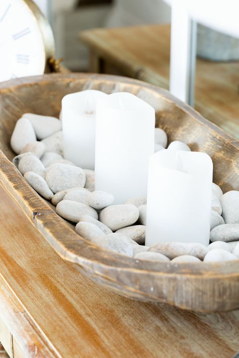 Fill a dough bowl with white river rocks and candles. Boho Dough Bowl Decor, Porch Table Centerpieces, Bowl Of Rocks Decor, Styling A Wooden Bread Bowl, Coastal Dough Bowl Decor, How To Style Dough Bowl, Simple Dough Bowl Decor, Coffee Table Bowl Filler, Dough Bowl Candle Decor