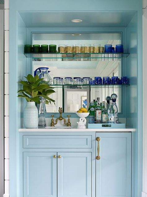 Glossy blue wet bar boasts powder blue cabinets donning brass hardware and holding a sink with an antique brass deck mount faucet beneath glass shelves mounted in front of a mirrored backsplash. Wet Bar Cabinets, Bar Nook, House Dressing, Built In Bar, Blue Cabinets, Wet Bars, Kitchen Views, Mobile Bar, Transitional Kitchen