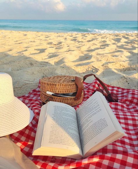 At the beach on the sand: a red and white gingham picnic cloth on top of it an open book, an open basket material crossbody bag coming out of it pens, and a white jute hat next to them with the sea in the background Books On The Beach, Read On The Beach, Reading On The Beach, Beach Book, Beach Books, Beach Cafe, Sea Photography, Book Cafe, Book Aesthetics