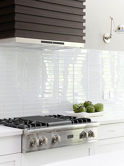 Modern white kitchen with stacked 2 x 10" white glossy subway tile.  Installed in columns, not alternating brick pattern.  White countertop, cabinetry.  Dark wood hood. White Glass Backsplash, Contemporary Backsplash, Glass Backsplash Kitchen, Modern Kitchen Backsplash, Subway Tile Backsplash Kitchen, Kitchen Vent, White Kitchen Backsplash, White Tile Backsplash, Subway Tile Kitchen