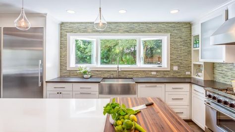 A 9-foot long window was added over the sink in this charming contemporary kitchen, creating lots of natural light in the space. The mood is kept bright and fresh with white cabinetry and a mottled green backsplash. Long Kitchen Window, Kitchen With Green Backsplash, Windows Above Sink, Kitchen Window Over Sink, Kitchen Windows Above Sink, Window Above Sink, White Contemporary Kitchen, Green Tile Backsplash, Above Kitchen Sink