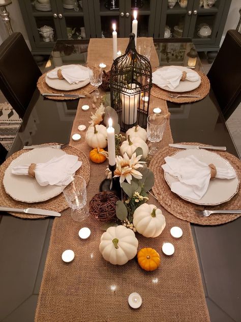 Tablescape with burlap runner, rattan chargers, simple white china and an assortment of pumpkins and candles Burlap Thanksgiving Table, Outdoor Pumpkin Decor, Simple Fall Tablescapes, Burlap Table Decorations, Pumpkins And Candles, Thanksgiving Decorations Table Setting, Harvest Dinner Party, Thanksgiving Runner, Simple Thanksgiving Table Decor