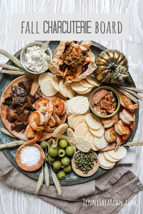 An image for a fall seafood platter with tuna jerky, sauteed shrimp, canned salmon, seachi, olives, capers, crackers and Boursin cheese on a wooden table with a tan napkin. Winter Platter, Seafood Board, Fall Charcuterie Board, Fall Charcuterie, Fall Appetizer, Pool Party Food, Fall Appetizers, Cheese And Crackers, Cranberry Chutney