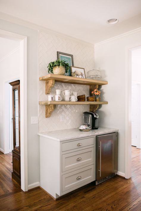 coffee station beverage cooler keurig coffee maker reclaimed wooden shelves herringbone subway tile carrara mable cup pulls vignette moonshine  winterwood hardwood floors banquette kitchen design kitchen renovation blindsgalore.com custom cabinets glass front cabinets stainless steel dishwasher newlyweds new life together couples heart of the home food preparation Kitchen Cart Coffee Station, Beverage Station With Floating Shelves, Coffee Bar Glass Cabinet, Ikea Beverage Station, Small Beverage Station, Coffee Maker In Kitchen, Coffee Cabinet Station, Home Coffee Corner, Banquette Kitchen