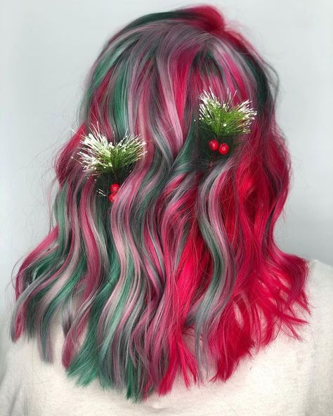 A festive hairstyle featuring pink and green streaks running through soft waves, accented with pine and berry hairpins. Perfect for holiday events, this fun and festive look combines natural decorations with bold, bright colors. Pink And Green Highlights, Christmas Hair Color Ideas, Christmas Hair Color, Bold Highlights, Holiday Hair Color, Green Hair Dye, Pink Streaks, Brown Curls, Vivid Hair Color