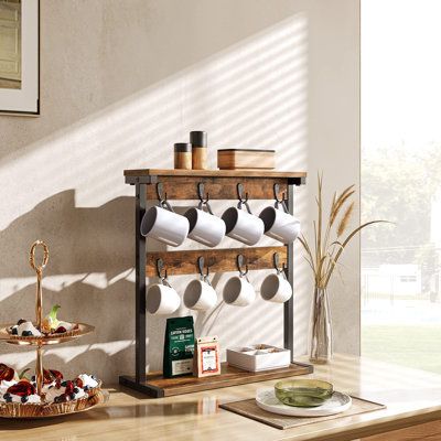 This mug holder stand has 8 hooks that can hang mugs, coffee cups or tea cups etc. and 2 open shelves as the reasonable place for goblets or wine cups, so that you can prepare your favourite drink at any time.This mug tree holder rack works better in saving space on the countertop. It can be placed on kitchen counters, dining tables, coffee tables, or cabinets to organize or display hanging items without wasting any small corners. High-class particleboard and iron pipes make this mug holder stan Mug Holder Stand, Shelves Organization, Coffee Mug Holder, Hanging Items, Kitchen Rustic, Mug Tree, Vintage Mug, Mug Holder, Kitchen Counters