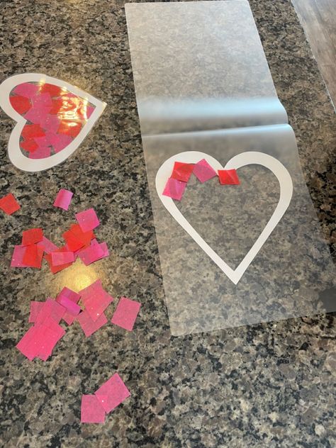 Fun kid Valentine activity craft! Cut out a heart with paper and using a laminating sheet, place cut up tissue paper squares in the middle of the heart. Laminate and hang on the window! Valentines Day Tissue Paper Crafts, Tissue Paper Valentine Craft, Contact Paper Heart Craft, Heart Suncatcher Craft For Kids, Kids Valentines Activities, Science Activities For Toddlers, Valentine Activity, Vday Crafts, Science Valentines