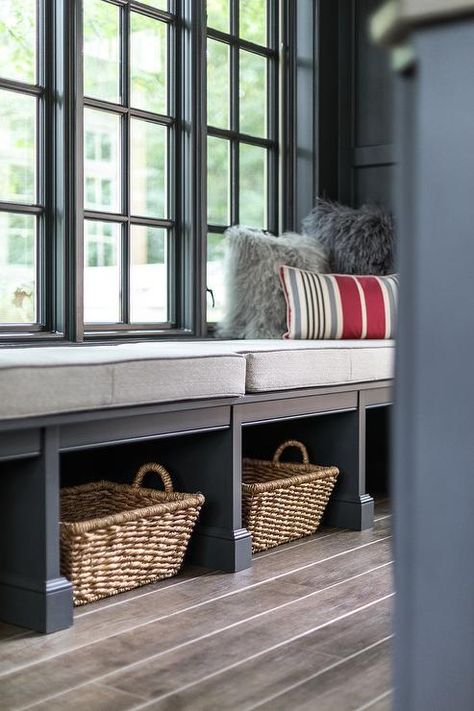 Gorgeous gray mudroom features windows accented with gray molding and positioned above a gray bench topped with light gray cushions and gray shag pillows layered behind a gray and red striped lumbar pillow. Mudroom With Window In Middle, Mudroom Window, Shag Pillows, Gray Mudroom, Gray Shag, Coat Room, Transitional Laundry Room, Hallway Seating, Window Bench Seat