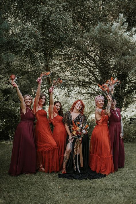 Bride in black dress for wedding in Devon standing with bridesmaids in mismatched burgundy and burnt orange bridesmaid dresses holding burnt orange dried flower bouquets | Katy Jones Photography Burnt Orange Burgundy Black Wedding, Burnt Orange Black Wedding, Witch Bridesmaid, Burnt Orange Bridal Party, Mismatched Burgundy Bridesmaid Dresses, Orange And Burgundy Wedding, Halloween Bridesmaid Dress, Bridesmaid Dresses Burnt Orange, Black Dress For Wedding