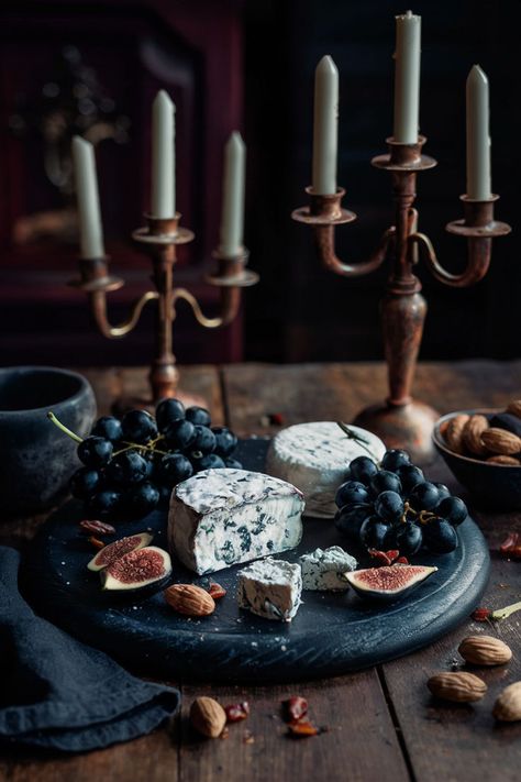 Rustic cheese board with dark wood featuring blue cheese, dark grapes, figs, and nuts, set on a wooden table with gothic candelabras and rich, moody lighting. Academia Food, Cheese Board Aesthetic, Dark Academia Food, Cheese Board Ideas, Board Aesthetic, Board Ideas, Dining Experiences, Dark Academia, Dark Aesthetic