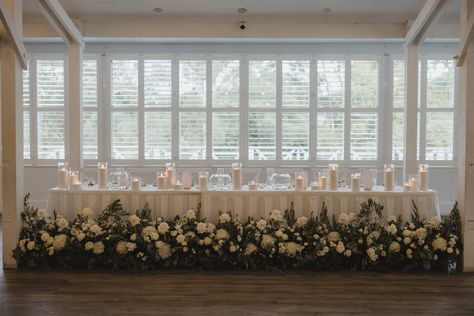 Stunning floral arrangements on the  floor of the bridal table with pillar candles adorning the the  top! Photography: 📸T-One Image Behind Head Table Decor, Head Table Florals, Floor Arrangements, Head Table Wedding Decorations, Table Florals, Table Floral Arrangements, Tables Wedding, Head Table Decor, Head Table Wedding