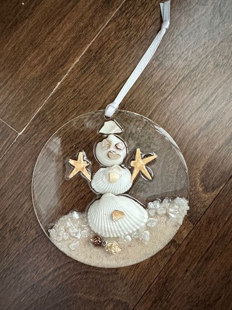 Beautiful snowman acrylic disk ornaments. Many other styles to pick from my Etsy store,  christmas tree, wave, wreath, all made with crushed glass /miroir, real sand, starfish, shells and resin. Decorated with ribbons to hang. Ready to ship. Size is 4" The colour may vary due to lighting. This listing is for 1 ornament. Please be aware resin is a challenging substance to work with as it is very unpredictable. These pieces are handmade and may have micro bubbles and slight imperfections.  If you Resin Seashell Crafts, Disk Ornaments, Resin Shells, Sand Starfish, Store Christmas Tree, Ocean Ornaments, Seashell Gifts, Blue Mussel, Nautical Ornaments