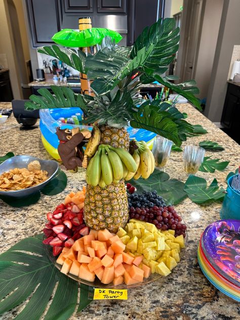 This was easy and fun. Just cut top off one pineapple and bottom off another so flat then used 4 wooden skewers to connect like pilings. Got the mini bananas and used smaller pieces of skewers to hang them & donkey kong himself. Added some cheap banana leaf decor from amazon to make the top of banana tree. Chopped fruit on the bottom! Donkey Kong Party Decorations, Donkey Kong Birthday Party Decorations, Mario Fruit Tray, Banana Themed Birthday Party, Donkey Kong Cake, Donkey Kong Birthday Party, Donkey Kong Party, Country Themed Parties, Banana Party