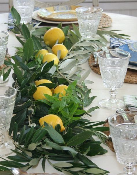 Layer fresh herbs down the center of the table  and finish off with a few lemons placed on top of the  fragrant herbs. Italian Style Table Decor, Italian Lunch Table Setting, Appertivo Party, Italian Inspired Table Setting, Italian Aesthetic Party, Italian Table Decorations Dinner Parties, Italian Rehersal Dinner Theme, Italian Dinner Party Table Settings, Italian Anniversary Party Ideas