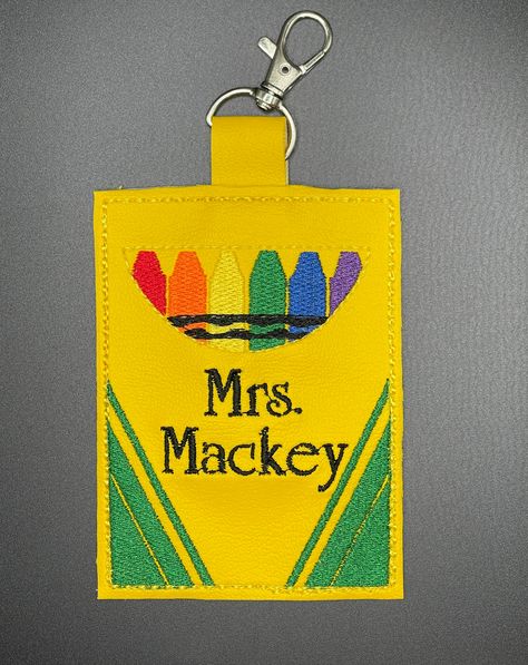 "This crayon-inspired, machine embroidered ID badge holder with lanyard is perfect for the teacher in your life. The 4\" x 3\" design fits the average size identification with a clear window on the back, so teachers can easily display their credentials. Personalize this cute accessory that screams creativity by choosing one of the four youthful fonts available. In the personalization box, include the desired name.  Colors shown in the photos will remain the same. If you would like a different variation, please send me a message. Black lanyard with clip included; measures ~17\"long /.4\" wide strap 🎁 Perfect Gift for Educators: Whether you're a teacher yourself or looking for a thoughtful gift, this badge holders make for a unique and cherished present. Show appreciation for the educators Teacher Lanyards, Black Lanyard, Badge Lanyard, Teacher Badge, Clear Windows, Crayon Box, Show Appreciation, Diy Teacher Gifts, Id Badge Holders