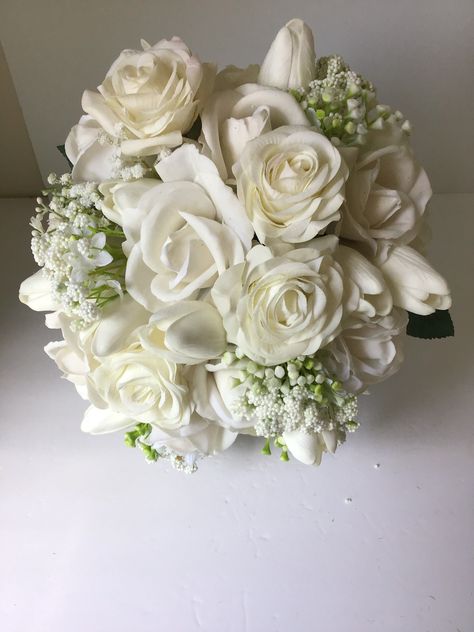 The "Michelle" classic real touch faux bridal bouquet. Featuring white roses, white tulips, and baby's breath. Bouquet is collared with faux rose leaves. Bouquet measures 10 inches across. White Wedding Flower Bouquets, Flowers White, Simple White Wedding Bouquets, White Rose Wedding Boquet, Just White Roses Bouquet, Petite White Rose Bouquet, White Garden Rose Bouquet, White Roses With Pearls Bouquet, White Wedding Flowers Bouquet