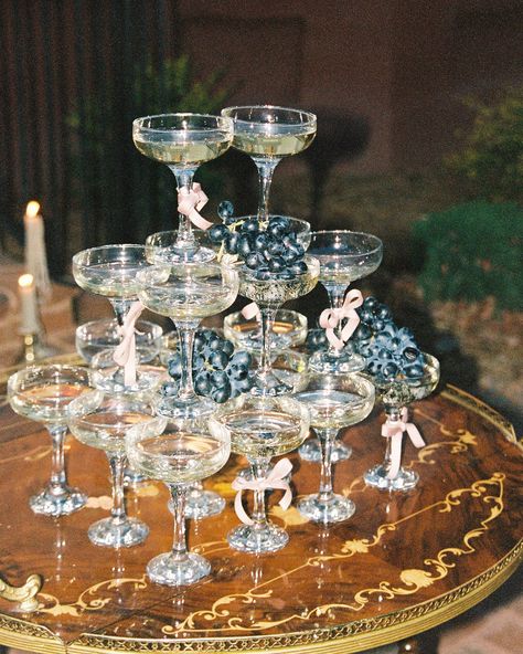 Champagne tower, vintage wedding, vintage wedding inspiration, coupe glasses, bows, bows on glasses, feather wedding dress, feather dress, champagne tower with fruit, champagne tower with grapes, anti bride, vintage wedding aesthetic, old hollywood aesthetic, hollywood wedding aesthetic, film, 35mm film, film wedding, film wedding photographer Stacked Champagne Glasses Wedding, Champagne Towers Wedding, Champagne Tower At Wedding, Vintage Champagne Tower, Champagne Glass Tower Wedding, Old Hollywood Aesthetic, Fruit Wedding, Wedding Dress With Feathers, Hollywood Aesthetic