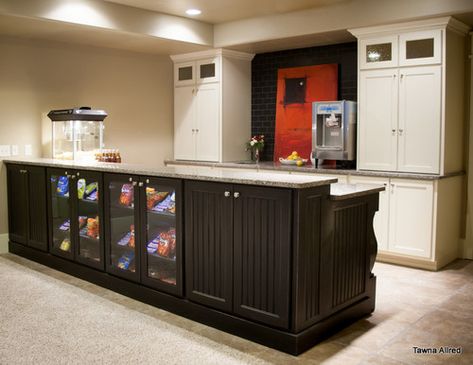 We designed this basement kitchenette to resemble that of a mini theater concession stand! Sleek black paneled cabinetry with a glass door display case is perfect for showing off your collection of sweets! A popcorn and soft ice cream machine are also a nice touch to this home theater - setting the mood for a cozy night in watching your favorite movie. Project designed by Star Valley, Wyoming interior design firm Tawna Allred Interiors. Basement Kitchens, Basement Kitchen Ideas, Star Valley Wyoming, Mini Theater, Ideas For Basement, Home Theater Basement, Basement Movie Room, Basement Kitchenette, Movie Theater Rooms