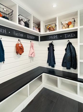 Stunning black and white mudroom features a glossy black l-shaped bench placed atop white shoe shelves and against a white shiplap trim finished with oil rubbed bronze assigned coat hooks fixed beneath a chalkboard border mounted under overhead shelves holding vintage metal bins. Beautiful Mudroom, Organized Mudroom, Vstupná Hala, Farmhouse Mudroom, Entry Room, Mud Room Entry, Mudroom Ideas, Mudroom Entryway, Mudroom Decor