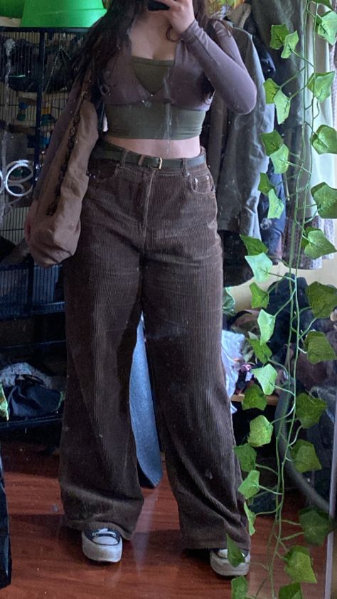 olive toned woman wears dark brown wide legged corduroy pants and a cropped long sleeve top layered over a green tank. Outfit is tied together by a gold buckled green leather belt, gold jewellery, a large brown tote bag with a long tiger eye keychain, and black platform converses. Dark Green Corduroy Pants Outfit, Green Corduroy Pants Outfit, Green Grunge Outfit, Thrift Manifest, Soft Autumn Palette, Corduroy Pants Outfit, Green Corduroy Pants, Autumn Palette, Outfit Grunge