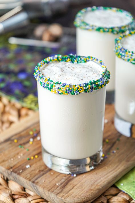 Close up of New Orleans Brandy Milk Punch in a clear glass with purple, green, and gold sprinkles around the rim.